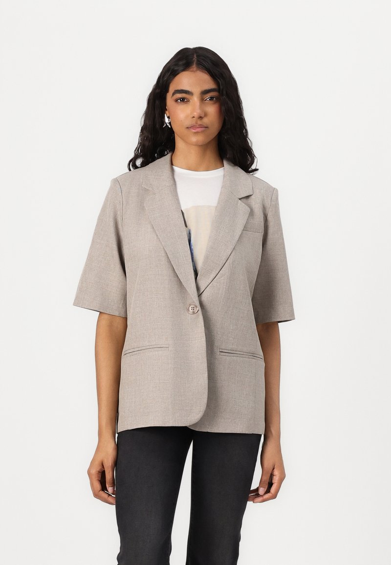Světlé šedé blazer s krátkým rukávem, klopovým límcem, zapínáním na jeden knoflík a předními kapsami. Měkká textilie, přiléhavý střih.