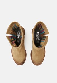 Botas de tobillo de ante color arena con diseño sin cordones, que presentan un forro de tela a rayas de colores y una suela de goma marrón cosida en contraste.