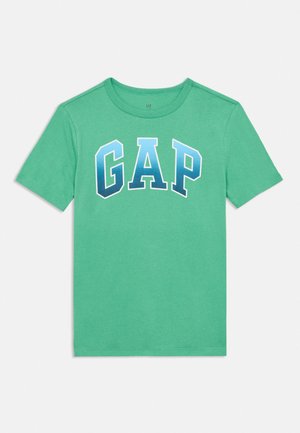 T-shirt vert à manches courtes avec des lettres dégradées bleues formant GAP sur la poitrine et un col rond.