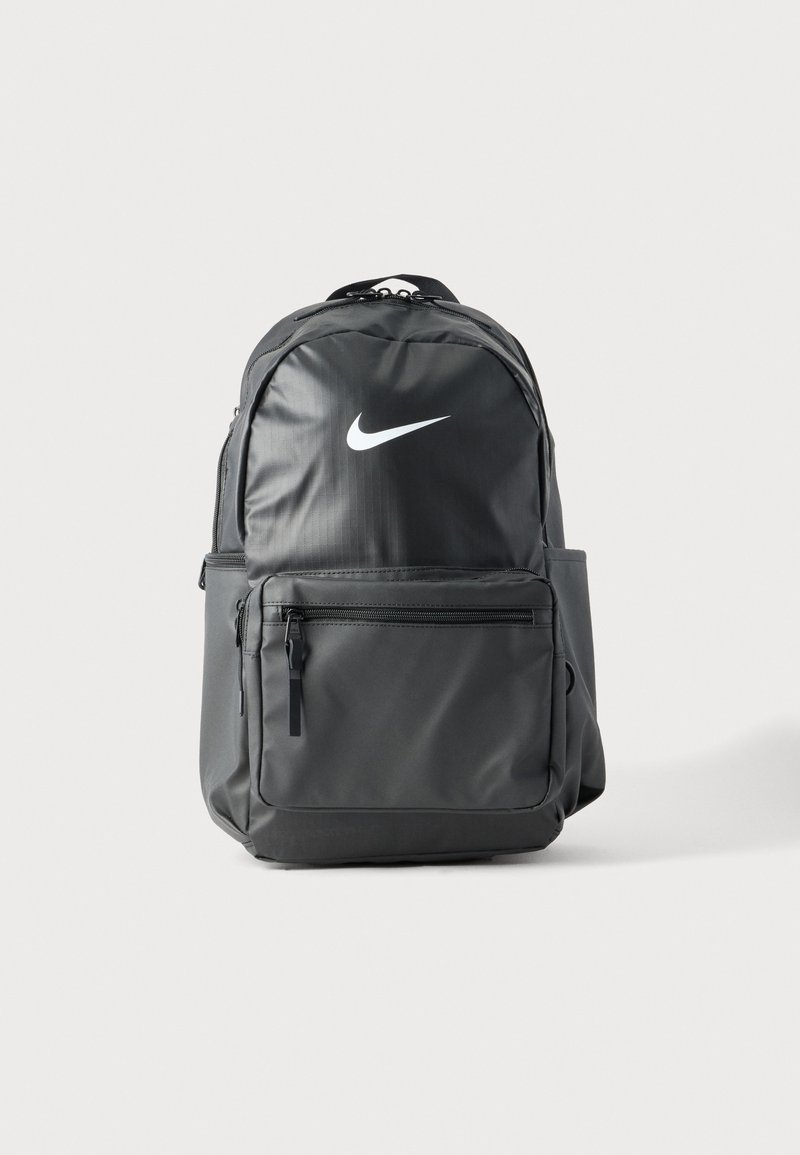 Μαύρο σακίδιο Nike με μπροστινή τσέπη με φερμουάρ, πλαϊνές τσέπες, επάνω χερούλι και λευκό λογότυπο swoosh σε απλό φωτεινό φόντο.