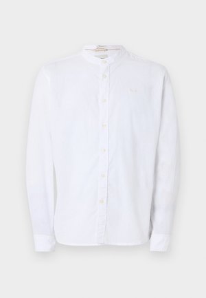 Valge pika varrukaga nööbitav särk mandariinkaeluse, nähtavate nuppude ja peene rinnataskuga ühevärvilisel taustal.