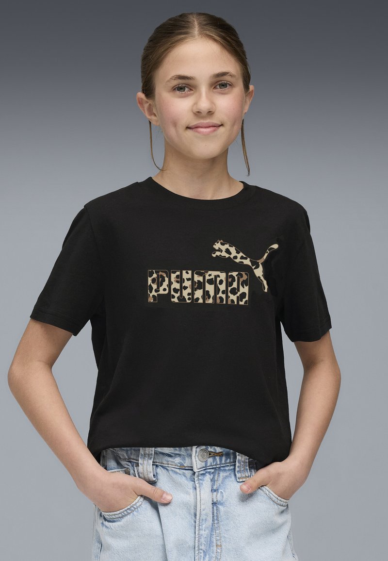 Črna bombažna majica s printom leoparda in logotipom "PUMA", ter stranskim oblikovanjem logotipa. Oblečena z svetlo modrimi denim kratkimi hlačami.