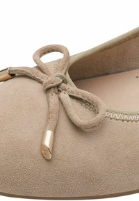 Ballerine en daim beige à bout rond, ornée d'un nœud décoratif noué avec des détails en métal doré aux extrémités du nœud.