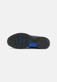 Nike athletic shoe sole in black rubber with blue accents. Features textured grip with rectangular and oval patterns for traction.