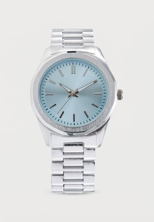 Orologio da polso in metallo color argento con quadrante azzurro chiaro, indici orari argento e cinturino metallico a maglie, che segna l'ora 10:09:36.