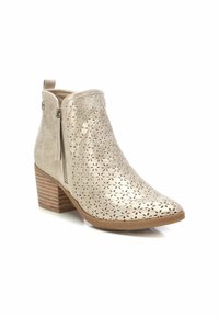 Stivaletti beige alla caviglia con punta appuntita, motivo floreale perforato, zip laterale e tacco a blocco impilato. Realizzati in materiale testurizzato.