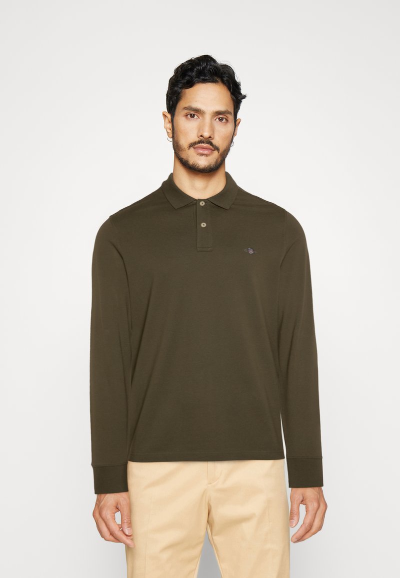Long-sleeve polo shirt in dark olive green, made of soft fabric with a collar and three-button placket, features subtle branding on the chest.