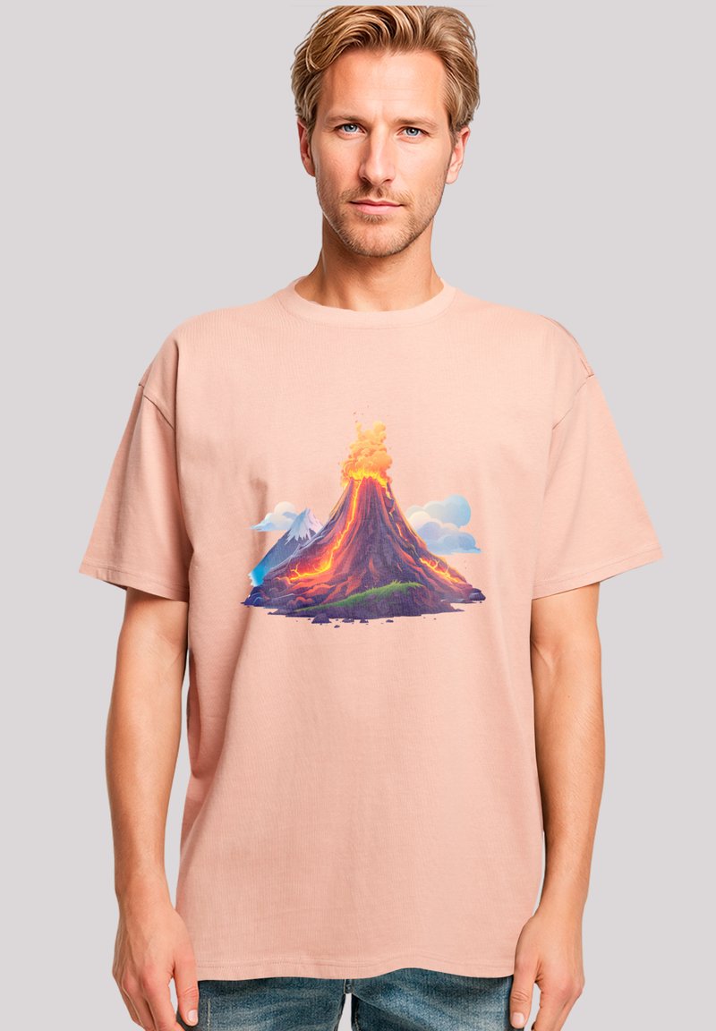 Light pink cotton t-shirt featuring a vibrant graphic of a volcano with orange lava, surrounded by clouds and mountains. Loose fit, short sleeves.