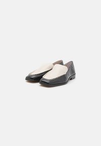 Melnas ādas loafers ar krēmkrāsas gludu ādas augšdaļu, ar dekoratīvu šūtu akcentu gar malu un zemu papēdi.