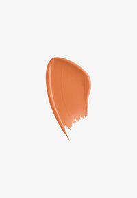 Échantillon de maquillage liquide couleur pêche. Texture lisse et brillante avec une consistance légèrement épaisse et un bord pointu, montrant des traces de pinceau.