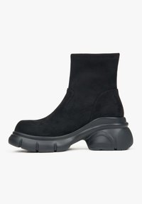 Black ankle boots made of suede with a chunky rubber sole. Features a smooth finish and rounded toe, with a seamless shaft design.