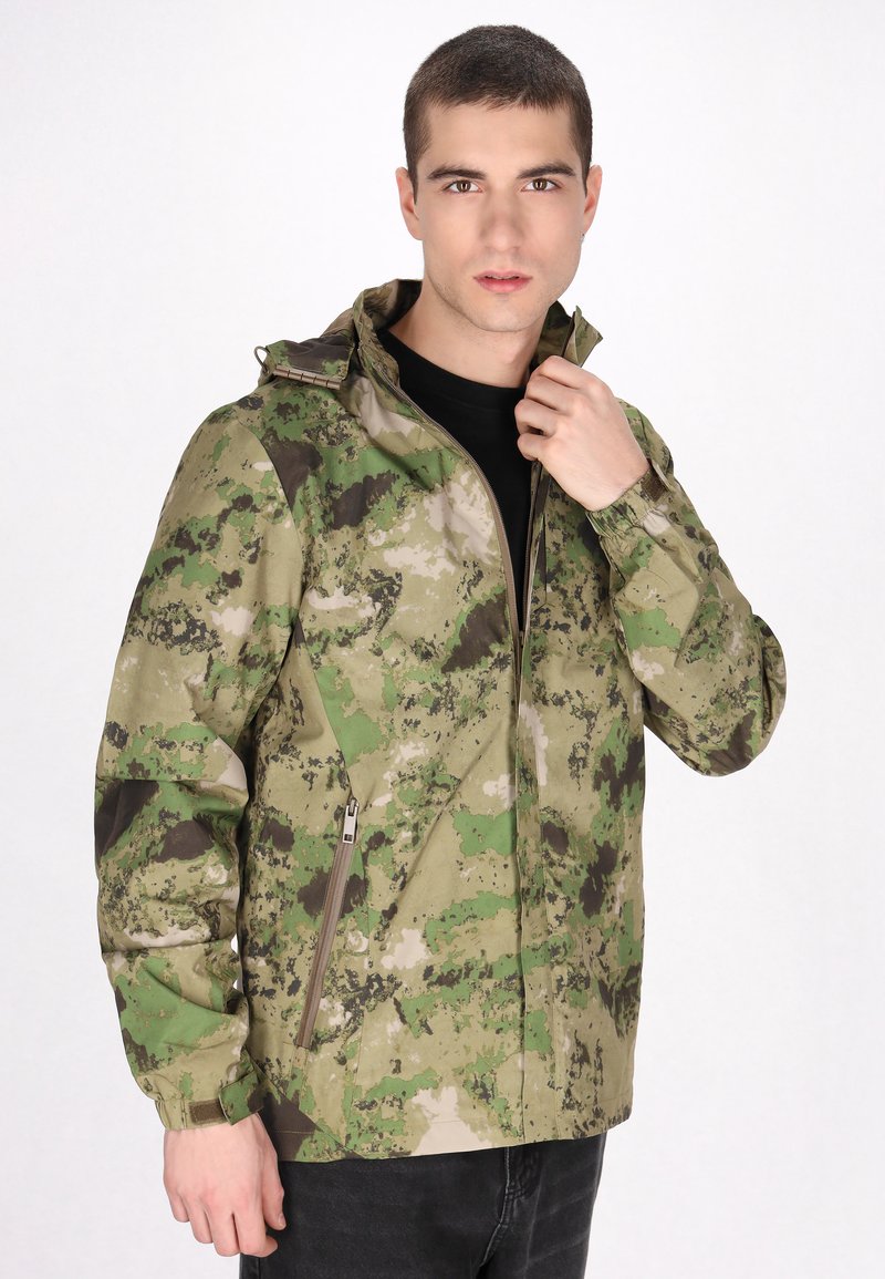 Camouflagejack in groene en bruine tinten, met een rits aan de voorkant, capuchon, verstelbare manchetten en een zijzak met rits. Gladde stoftextuur.