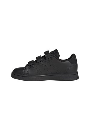 Zapatilla negra de corte bajo con tres tiras de velcro, paneles laterales perforados y suela texturizada, mostrada de perfil sobre un fondo blanco.