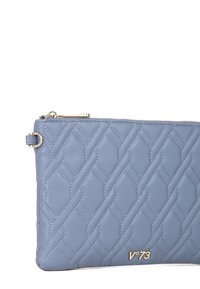 Clutch de piel acolchada azul con cierre de cremallera, que presenta un logo en tono dorado y un sutil patrón de diamantes en la superficie.