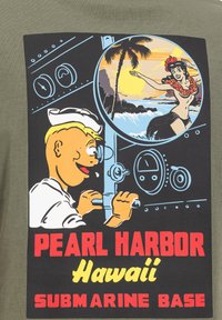 Olivengrøn t-shirt med en grafik af en sømand og en hula danser, fed sort baggrund og farverig tekst: "Pearl Harbor Hawaii U-bådsbase."