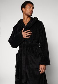 Black fleece bathrobe with a hood, long sleeves, tied waist, and front pockets. Soft texture with a plush appearance.