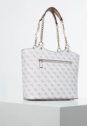 Witte draagtas met een bruin herhalend logopatroon, gouden kettinghandvatten met leren grepen en een voorvak met rits, geplaatst op een wit voetstuk.