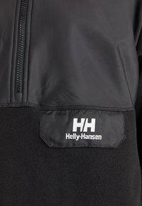 Pull noir en polaire avec col montant et fermeture éclair. Équipé d'un corps en polaire noir texturé et d'une partie supérieure en tissu noir brillant. Logo Helly Hansen affiché.