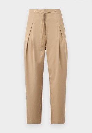 Μπεζ κωνικά παντελόνια με πιέτες στο μπροστινό μέρος και στυλ με κορδόνι στη μέση, παρουσιάζονται πάνω σε ένα απλό ανοιχτό φόντο.