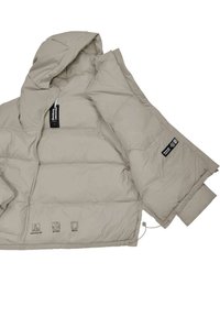 Tan pufferjack met een capuchon, ritsluiting en elastische manchetten. Kenmerkt waterafstotende stof, gerecycleerde isolatie en verzorgingssymbolen op de zoom.
