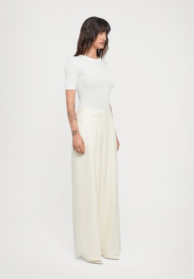 White short-sleeve fitted top paired with high-waisted, light cream wide-leg trousers. Smooth fabric with a clean, minimalistic design.