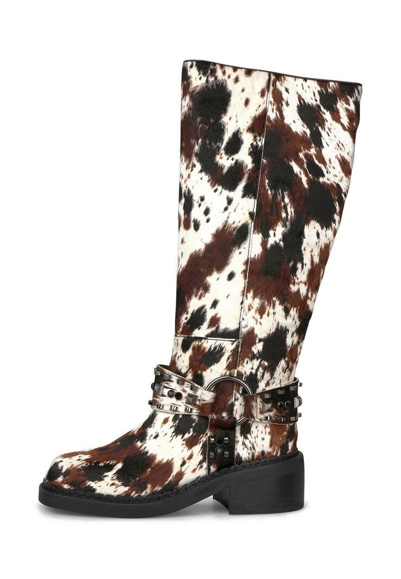 Bota alta con un patrón de piel de vaca marrón, negro y blanco, que presenta una correa decorativa con tachuelas metálicas y un anillo sobre la suela negra y el tacón bajo.