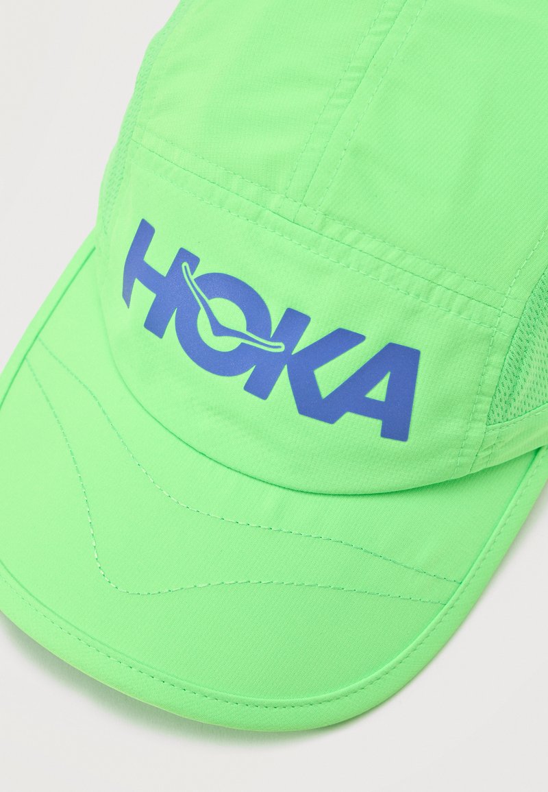 Bright green lightweight cap with blue HOKA logo and mesh side panels, designed for athletic use.