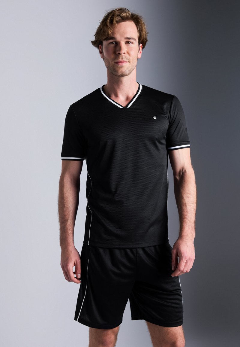 Conjunto atlético negro que incluye una camiseta de cuello en V y mangas cortas, junto con pantalones cortos a juego, acentuado con ribetes blancos y un patrón de tela texturizada.