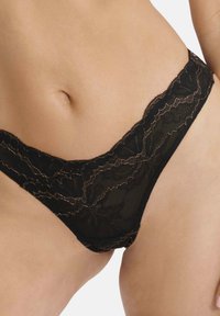 Czarny koronkowy string z misternymi wzorami kwiatowymi i falbaniastym wykończeniem. Materiał ma delikatną fakturę z subtelnym połyskiem.