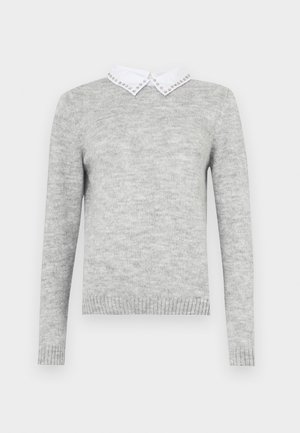 Pilkas megztinis su ilgomis rankovėmis, turintis baltą apykaklę papuoštą dekoratyviais varžtais. Pagamintas iš minkštos, tekstūruotos medžiagos.