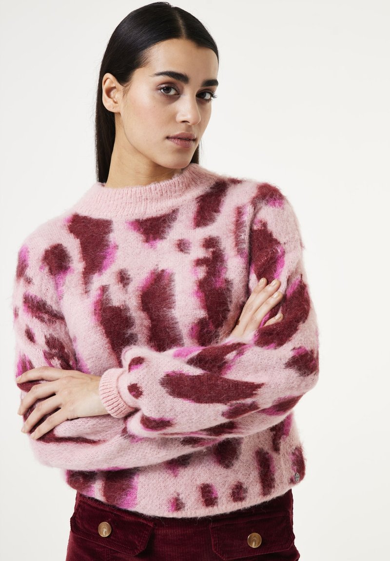 Pull en tissu pelucheux avec un motif rose et bourgogne, col ras du cou et poignets côtelés, présentant des éléments de design abstrait.