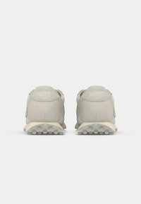 Nike tenisice od svijetlosive zamjene s elegantnim dizajnom, imaju teksturiranu potplat za prianjanje i Nike logo na peti.