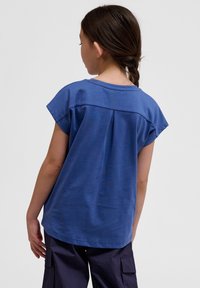 Blaues Kurzarm-T-Shirt aus weicher Baumwolle, mit rundem Ausschnitt und Falten detail auf der Rückseite, im lockeren Schnitt.