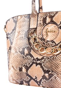 Borsa grande con stampa serpente beige e nera. Presenta hardware dorato, un accentuazione a catena e una toppa con logo circolare. Superficie testurizzata.