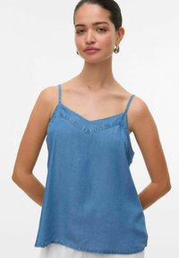 Top in denim azzurro chiaro con spalline sottili, scollo a V e vestibilità ampia. Dettagli di cucitura minimi lungo il collo.