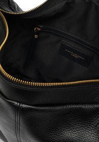 Interno di una borsa in pelle nera con una cerniera d'oro. Presenta una fodera in tessuto morbido e una piccola tasca con zip etichettata "GIANNI CHIARINI FIRENZE."