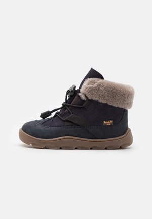 Botte d'hiver bleu marine pour enfant avec bordure en fausse fourrure beige, fermeture à lacets à bouton-pression et semelle en caoutchouc marron estampillée "froddo tex".