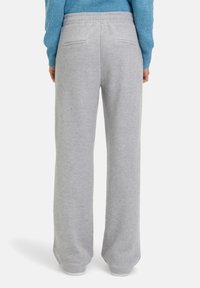 Grijze joggingsbroek met een ontspannen pasvorm, elastische tailleband en twee achterzakken. De stof heeft een zachte textuur en een licht geborstelde afwerking.