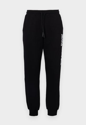 Sorte joggebukser laget av myk stoff, med elastisk midje med snor, innsnevrede ben og en logo langs siden.