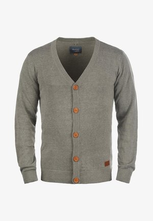 Pilkas megztinis, pagamintas iš audinio, su V formos iškirpte, penkiomis medinėmis sagomis, raukšlėtomis rankogaliais ir apatine dalimi, su mažu ruduo ženkliuku šone.