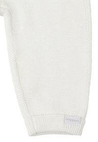 Pantalons pour bébé en tricot blanc avec des poignets côtelés. Présente une petite étiquette avec le nom de la marque "noppies" près du bas à gauche. Texture douce.