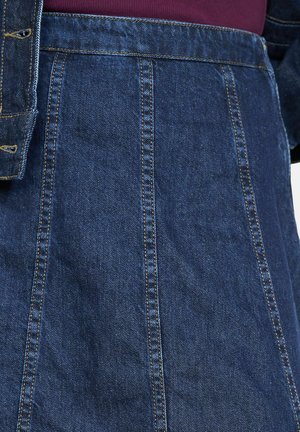 Jeans krilo temnoblene barve, ki se ponaša z navpičnimi šivi in strukturiranim dizajnom. Material je mehak in z rahlo teksturirano površino.