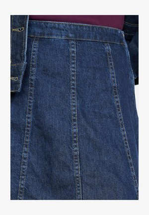 Džinsu svārki tumši zilā krāsā, ar vertikālām šuvēm un strukturētu dizainu. Materiāls ir mīksts ar nedaudz teksturētu virsmu.