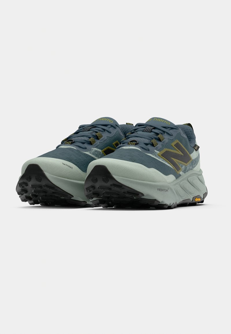 Trail running shoes featuring a dark teal upper, black accents, textured rubber outsole, and a light mint-colored midsole with branding details.
