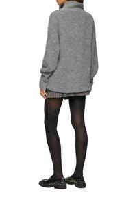 Grau strukturierter Pullover mit hohem Kragen, langen Ärmeln und lockerer Passform, kombiniert mit gestreiften Shorts und schwarzen blickdichten Strumpfhosen.