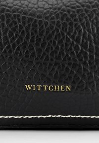 Zwarte lederen portemonnee met een gestructureerd oppervlak, voorzien van een gouden "WITTCHEN" logo en witte stiksels langs de rand.