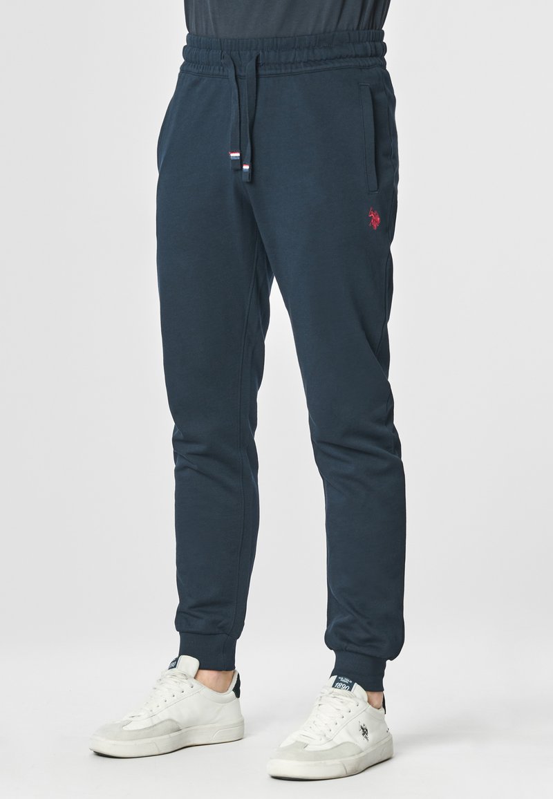Jogger blu navy realizzati in morbido tessuto, con vita elastica e coulisse, tasche laterali e un piccolo dettaglio con logo rosso.