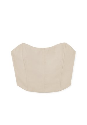 Bežs bezpiedurkņu tops ar strukturētu, pieguļošu dizainu. Ar izliektiem malām, redzamām šuvēm un gludu auduma tekstūru.