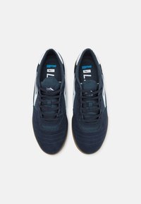 Marineblaue Sportschuhe aus Wildleder und Mesh-Materialien, mit weißen Akzenten, strukturiertem Finish und runden Gummisohlen.