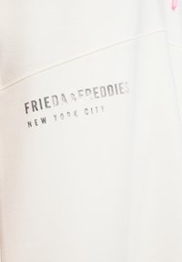 Witte sweatshirt met een metallic zilver bedrukt logo dat "FRIEDA & FREDDIES NEW YORK CITY" leest. Glad van textuur met gestikte naden.